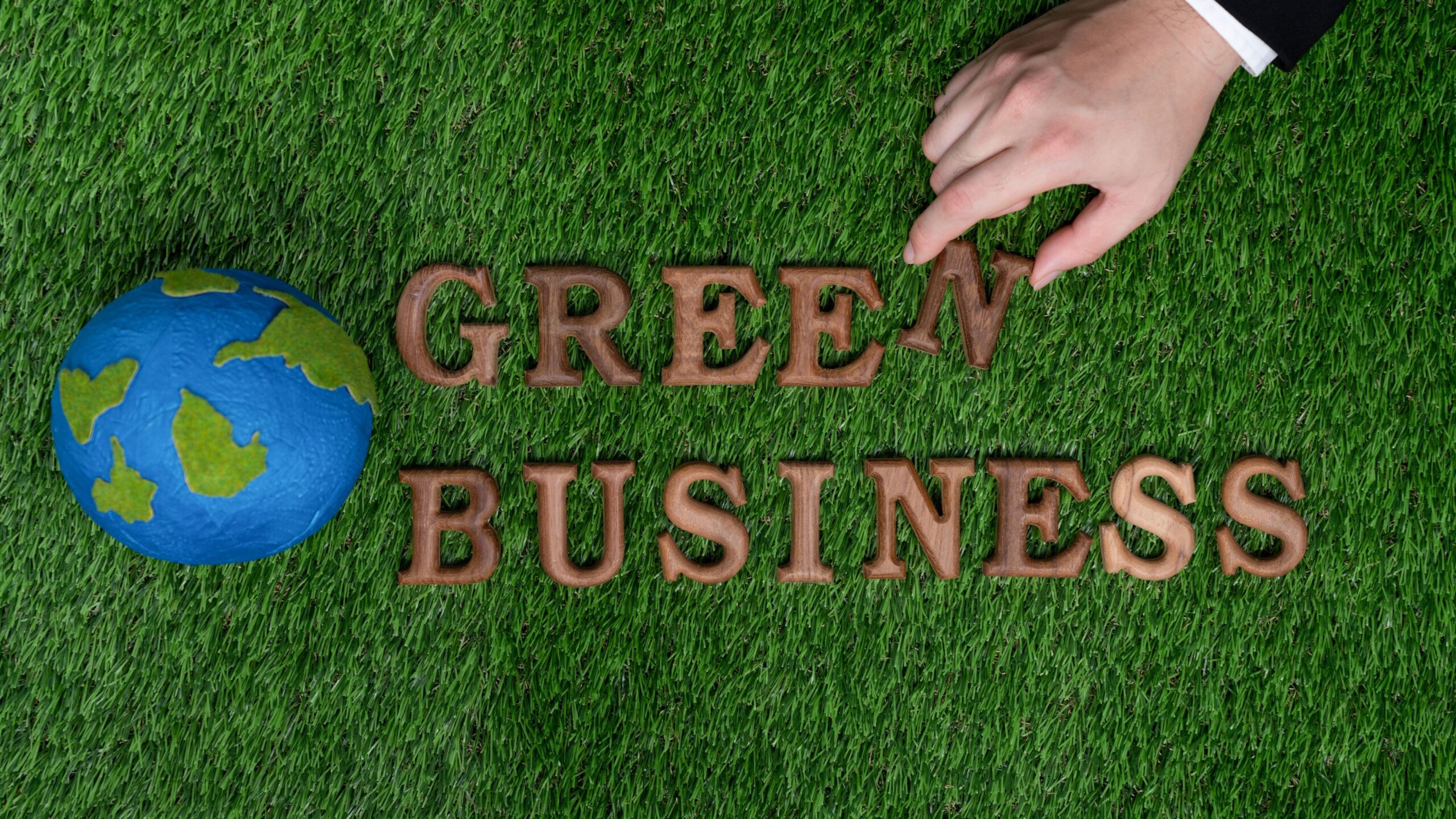 Businessman's hand arrange message in Green Business as concept of corporate effort to commitment to CSR or corporate social responsible concept for environmentally sustainable. Gyre