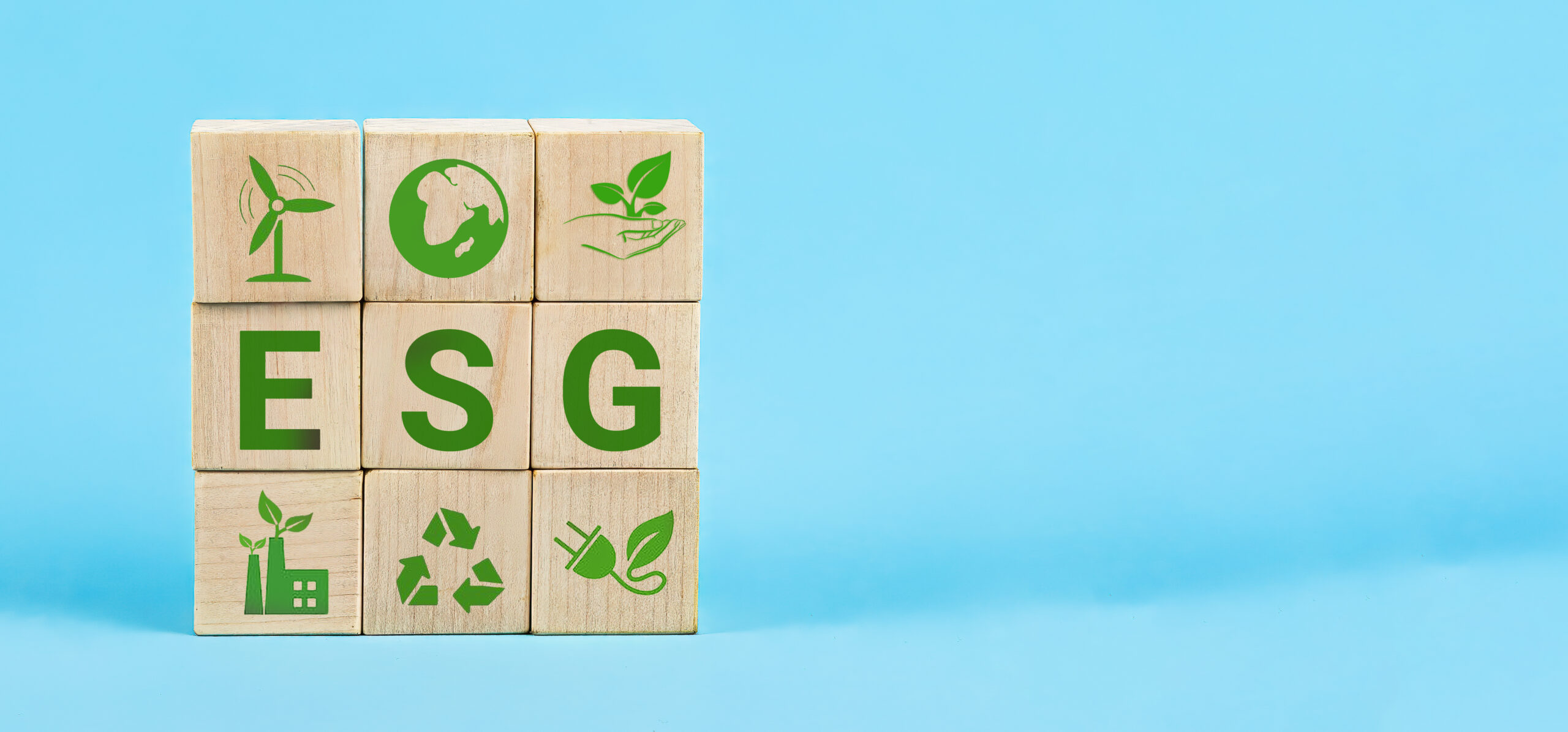 ESG Words on a wood cubes. ESG concept of environmental, social and governance. Wooden cube with abbreviation ESG standing with other icons on blue background