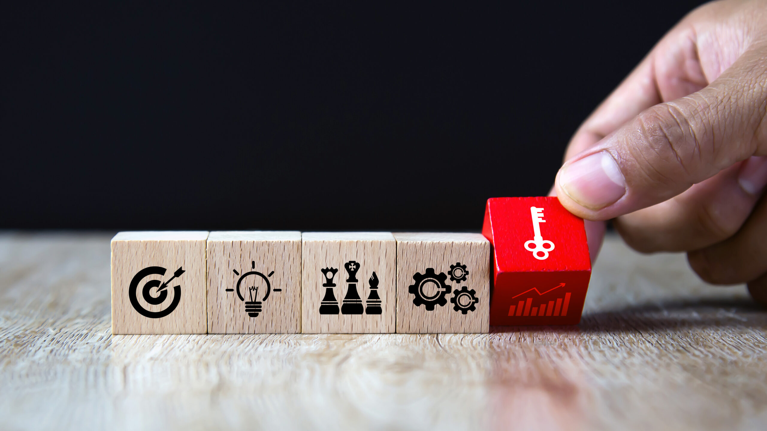 Hand choose wooden block stack with the key on business strategy icon.